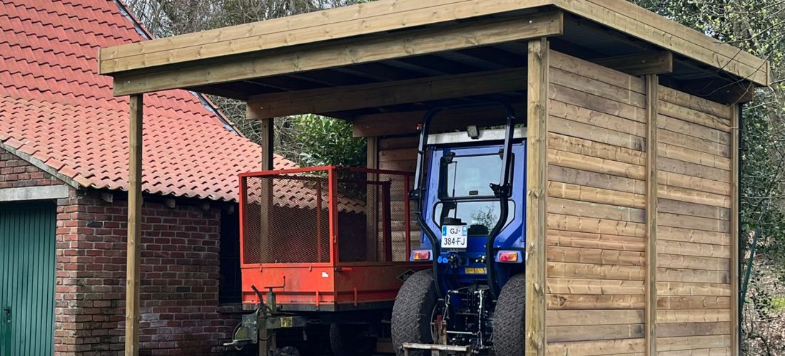 carport en bois abritant un tracteur et une remorque